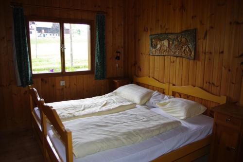 Cama en habitación de madera con ventana en Ferienhaus Forellenwirt en Grünbach