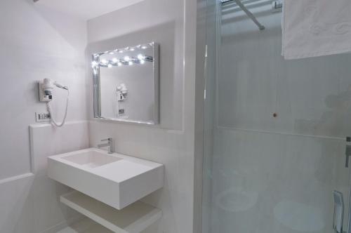 a white bathroom with a sink and a shower at Palazzo Favacchio - Patanè in Scicli