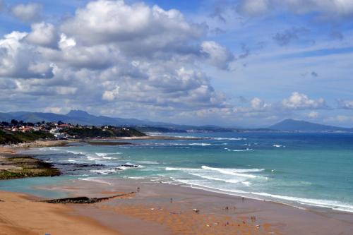 a beach with people on the sand and the ocean at Hôtel & Appart-hôtel Olatua in Bidart