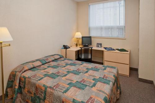 Habitación de hotel con cama y escritorio en Residence & Conference Centre - Oshawa en Oshawa