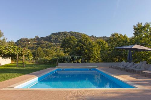 una piscina con sillas y sombrilla en Casa do Carvalho - Ponte de Lima, en Ponte de Lima