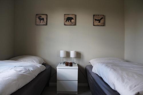 a bedroom with two beds and a night stand with two lamps at Das rote Haus hinterm Deich in Simonsberg