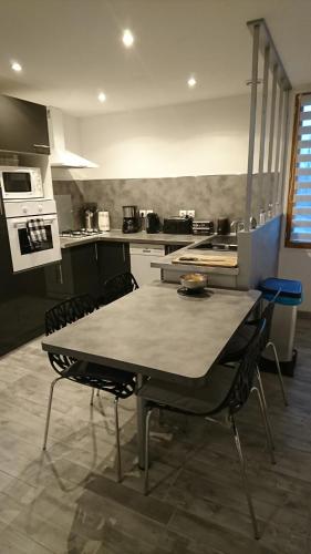 une cuisine avec une table et des chaises dans une cuisine dans l'établissement Les Dauphins, à Saint-Romain-de-Jalionas