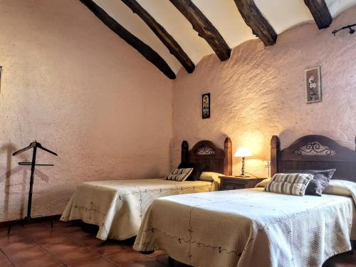 1 dormitorio con 2 camas y una cruz en la pared en Casa rural Las Masadas, en Cella