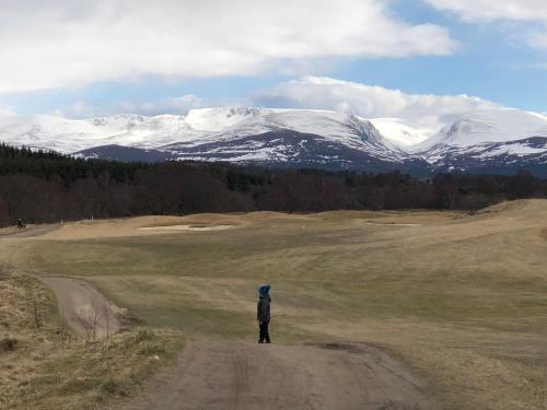a person standing on a dirt road looking at snow covered mountains at Ventoux in Aviemore