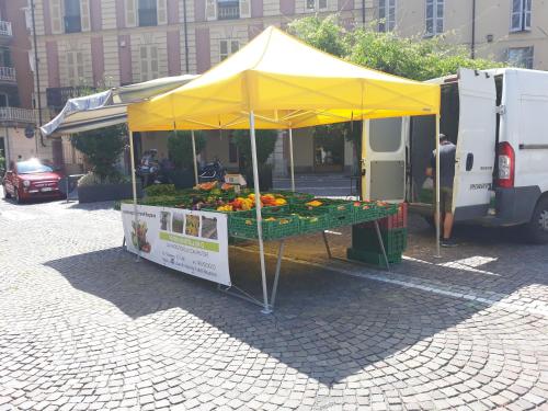a fruit stand with a yellow canopy on a street at Appartamento in centro storico in Asti