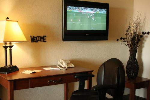 a room with a desk and a tv on a wall at Expressway Suites Fargo in Fargo