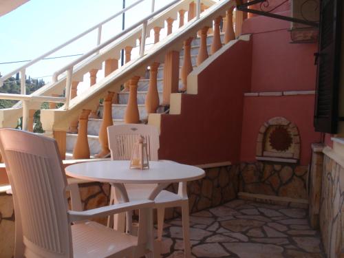 a table and chairs on a patio with stairs at Korina Studios in Paleokastritsa