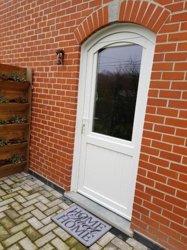 a white door in a brick building with a brick wall at LA RIVIERE DU BIEN ETRE in Chaumont-Gistoux