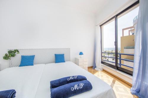 een slaapkamer met een groot bed en een groot raam bij Av. 1º de Maio in Costa da Caparica