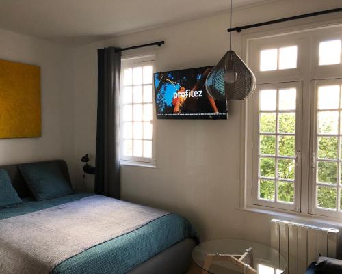 1 dormitorio con 1 cama y TV en la pared en Deauville centre, plage, casino et hippodrome, en Deauville