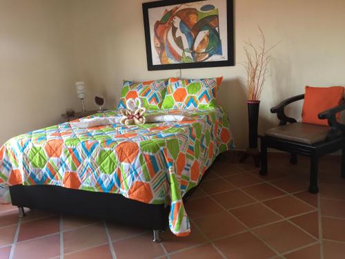 a bedroom with a bed with a colorful comforter at Oak Tree house in Guatapé