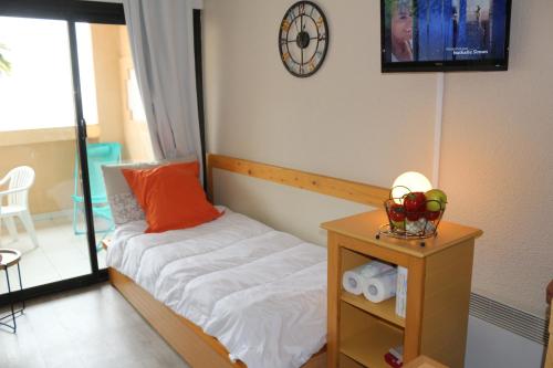 - une chambre avec un lit et une table avec une horloge dans l'établissement Appartement Palm d'Azur, à Cannes