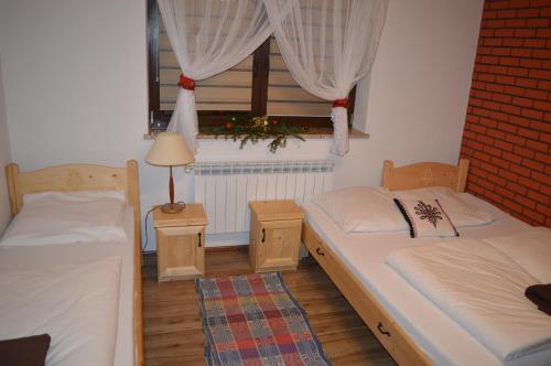 two beds in a room with a window at Domek pod Majową Górą in Kacwin