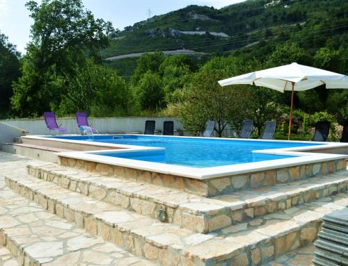 a swimming pool with chairs and an umbrella at Villa Bubalo in Omiš