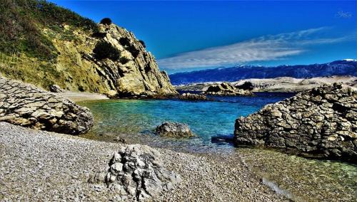a body of water with rocks and a mountain at Moon Stone Residence Pag in Pag