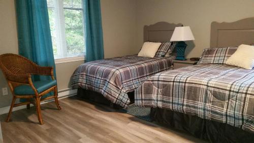 a bedroom with two beds and a chair and a lamp at Condo Lac Archambault 295 in Saint-Donat-de-Montcalm