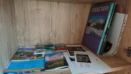 a pile of books sitting on a table next to a refrigerator at KUBO TATRY - Starý Smokovec in Smokovce