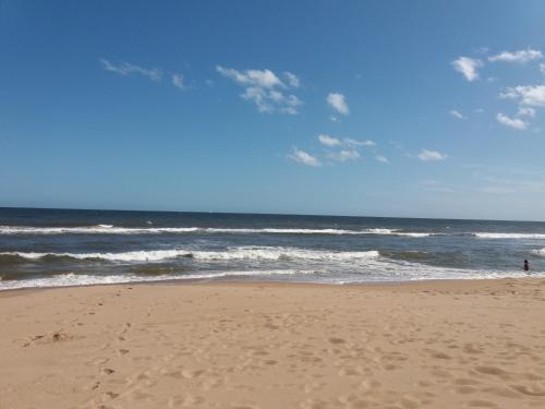 a beach with a person standing in the ocean at Aroma de mar casas en alquiler vacacional con hermosa piscina in Sauce de Portezuelo