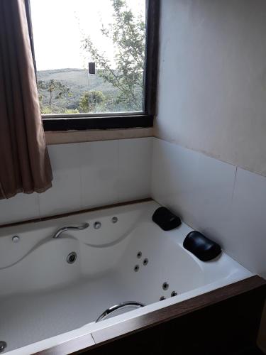 a bath tub in a bathroom with a window at Pousada Buieié in Lavras Novas