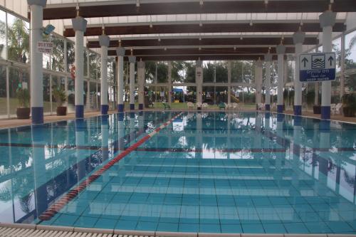 a large swimming pool with blue tiles in a building at The Beach Garden Apt. in Caesarea