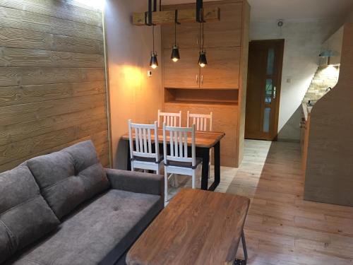 a living room with a couch and a table and chairs at Apartament Nad Potokiem in Szczawnica