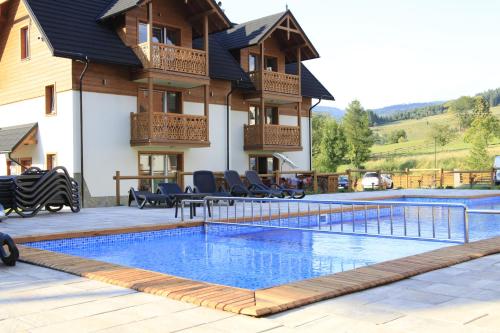 a swimming pool in front of a house at Apartament Nad Potokiem in Szczawnica