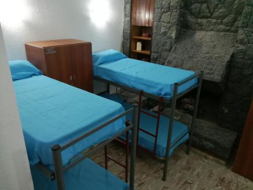 Tres camas en una habitación con pared de piedra. en Central Paz Hostel, en Villa Carlos Paz