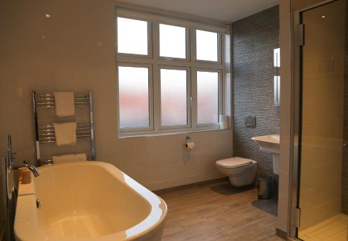 a bathroom with a tub and a toilet and a window at The Victory at Mersea in West Mersea