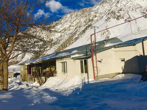 a house in the snow next to a mountain at Riverside Kazbegi in Stepantsminda