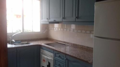 a kitchen with blue cabinets and a sink and a window at Nita Villa Altaona Golf Mosa Turquesa in Baños y Mendigo