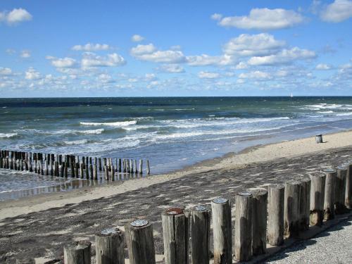 a beach with a wooden fence and the ocean at Westerschelde B&B in Vlissingen