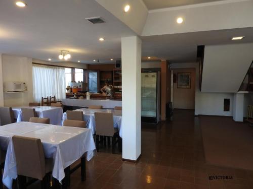 comedor con mesas y sillas blancas y cocina en Hotel Tiburones Club en Villa Gesell