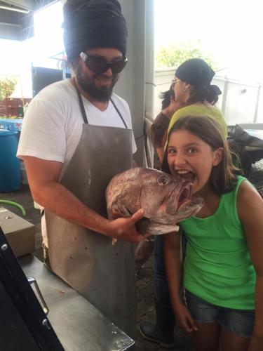 a man holding a girl holding a large fish at Pura Vida Hotel in Alajuela City