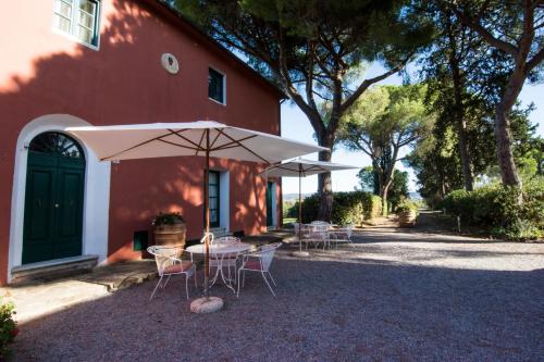 una mesa y sillas con sombrilla frente a una casa en Tenuta Col di Sasso, en Scarlino