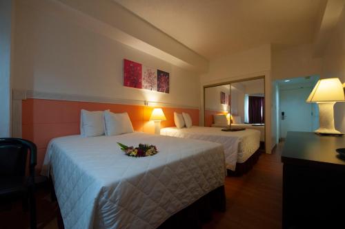 a hotel room with two beds with flowers on them at Grand Plaza Hotel in Tumon