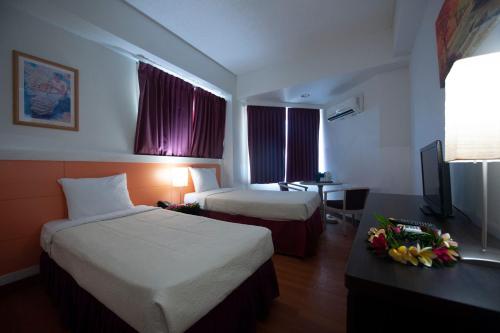 a hotel room with two beds and a desk at Grand Plaza Hotel in Tumon