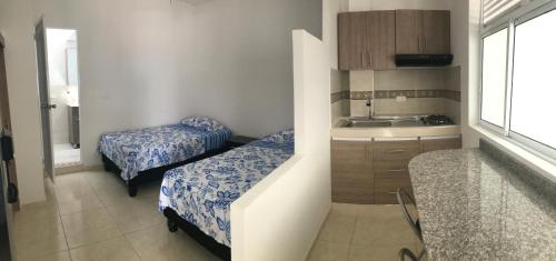 Una pequeña habitación con dos camas y un lavabo. en Cavas AP, en Cali