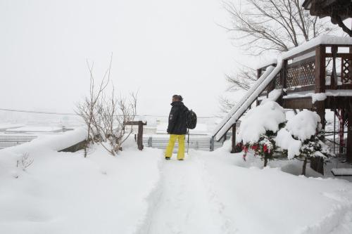 a man walking down a snow covered path at Sapporo Luxury Log House 5Brm max 18ppl 4 free parking in Sapporo