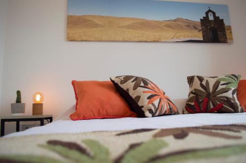 a bed with orange pillows and a picture on the wall at Cactus 1 in Salta