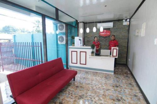 a restaurant with a red couch and two men at a counter at 7 Meadows Inn in Tagbilaran City