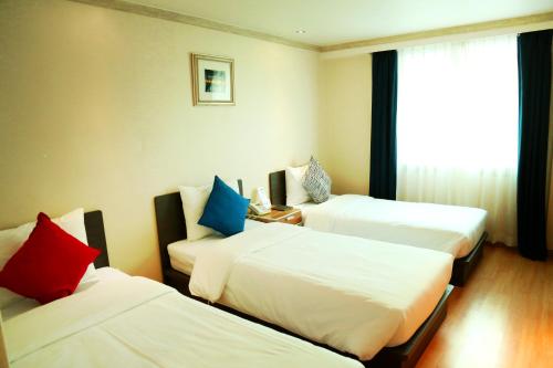 um quarto de hotel com três camas e uma janela em Lavita hotel em Seul
