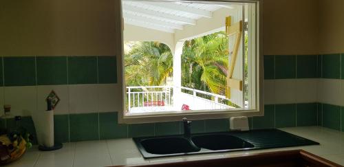 een keuken met een raam en een aanrecht met een wastafel bij La Belle Créole in Sainte-Anne