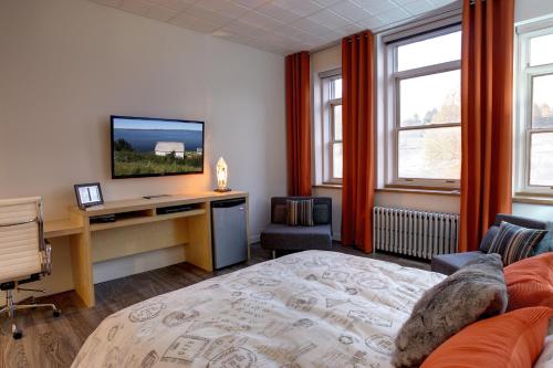 a bedroom with a bed and a desk with a television at Suite Marie-Thérèse in Vallée-Jonction
