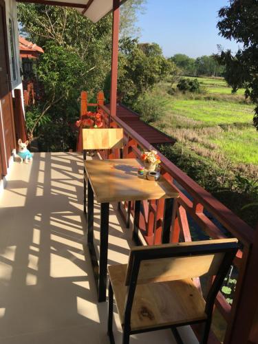 a table and chairs on a porch with a view of a field at Naraya Homestay in San Pa Tong