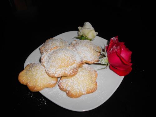 a white plate with cookies and a red rose at Albergo Sala in Valbrona