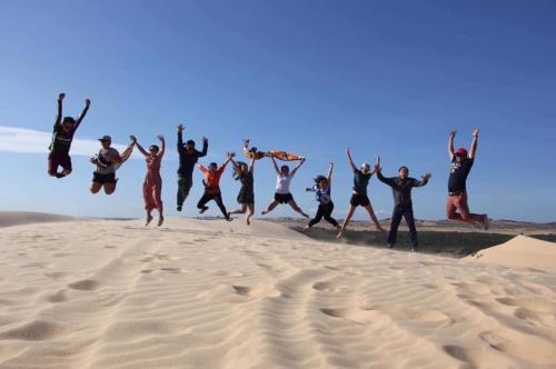 a group of people jumping in the sand at Hoang Nga Garden Guesthouse in Mui Ne