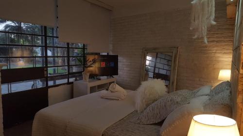 a bedroom with a bed with pillows and a television at Bidieen Inn Uruguay in Carrasco