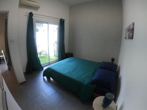 Un dormitorio con una cama verde y una ventana en F2 Crea Run en Saint-Pierre