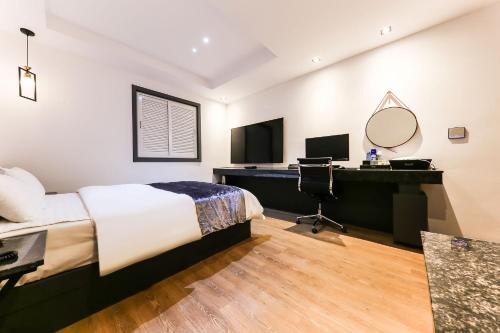 a bedroom with a bed and a desk and a mirror at Seosan Aria Hotel in Seosan